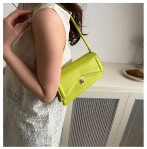 Detail of lime green shoulder bag featuring geometric stitching and gold metal buckle
