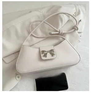 Dettaglio borsa sottobraccio bianco crema in similpelle con fibbia a fiocco argento su giacca
