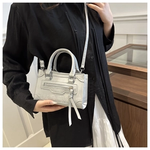 Vue détaillée d'un sac bandoulière gris texturé avec des glands et des clous métalliques