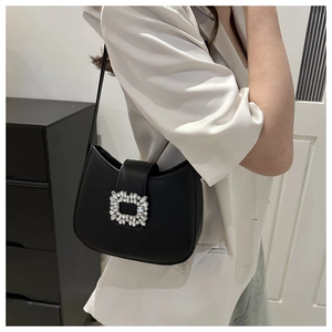 Elegant black crescent shoulder bag with a square rhinestone buckle on a white satin blazer