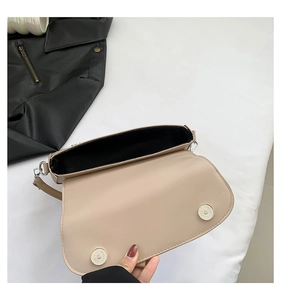Detail view of the beige saddle bag's interior featuring a double magnetic snap closure