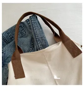 Detail of canvas tote bag with thick brown woven handles and secure zipper closure