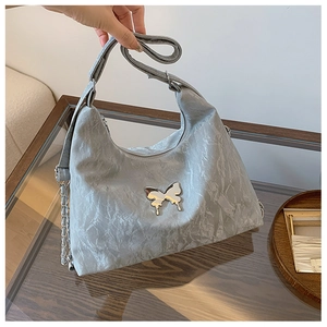 Detail of grey textured shoulder bag featuring silver butterfly buckle and wide strap