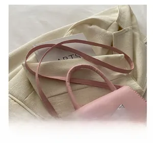 Detailed close-up of a pink mini crossbody bag with a silver bow and adjustable strap