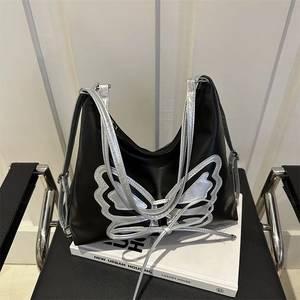 Minimalist black tote bag with silver butterfly applique on a designer chair