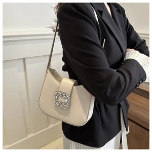 Détail du sac à bandoulière crème avec une boucle carrée scintillante en strass