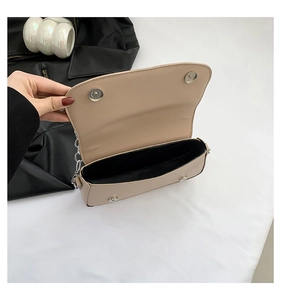 Detail view of beige saddle bag showing silver chain strap and magnetic closure