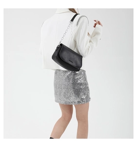 Detail of black leather saddle bag with chunky silver chain strap worn by a model