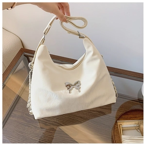 Close-up of cream leather shoulder bag featuring a metallic silver butterfly buckle