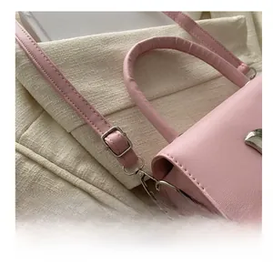 Close-up of the adjustable silver metal buckle and strap detail on a pink handbag