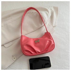 Detail of pink pleated crescent bag with silver butterfly buckle on white suit jacket