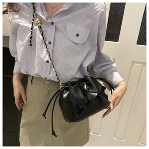 Détail du sac seau noir à nœuds avec bandoulière chaîne et perle dorée gravée