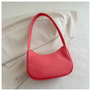 Close-up of pink PU leather crescent bag with silver zipper on a white blazer