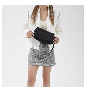 Detail of a minimalist black leather saddle bag with silver chain and dual straps