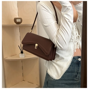 Detail view of the brown leather shoulder bag featuring triple gusset layers and gold clasp