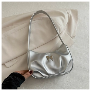 Detailed view of silver metallic textured crescent bag with a decorative 3D metal butterfly