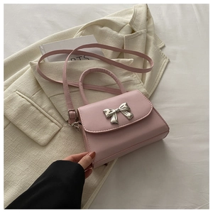 Close-up of pink mini crossbody bag with a silver bow buckle on elegant fabric