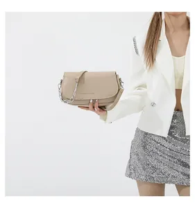 Detail of minimalist beige saddle bag with decorative silver chunky chain strap