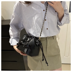 Détails du sac seau noir à cordon avec texture en cuir et trois nœuds décoratifs