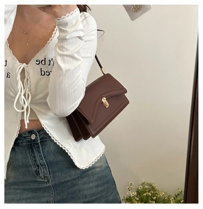 Detail of dark brown vintage underarm bag with gold clasp and triple accordion design