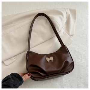 Close-up of brown pleated shoulder bag with silver butterfly metal ornament detail