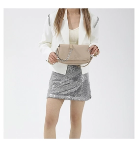 Detailed shot of beige crossbody bag with silver chain strap on a white blazer outfit