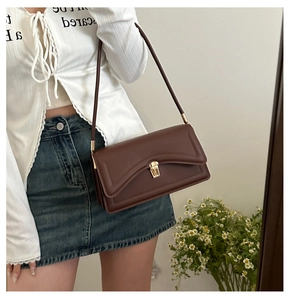 Detail of vintage brown rectangular shoulder bag with golden metallic lock and matte leather