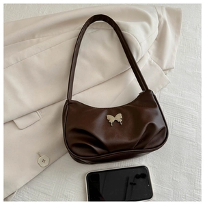 Close-up of dark brown crescent bag with silver butterfly charm and pleated faux leather