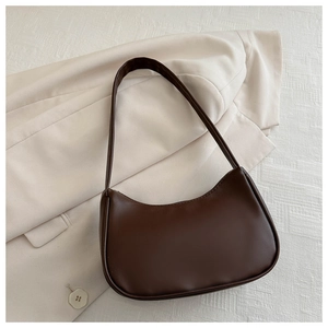 Detail of dark brown leather hobo bag placed on a stylish beige blazer