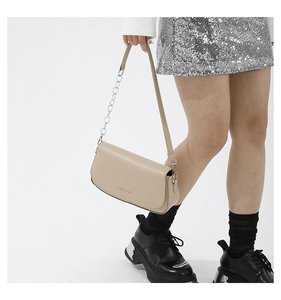 Beige saddle bag styled with silver chain and sequin skirt in a fashion studio