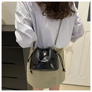 Detail of black leather bucket bag with bow decorations and elegant chain strap