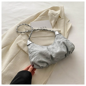 Close-up of silver pleated dumpling bag with metallic texture and woven strap