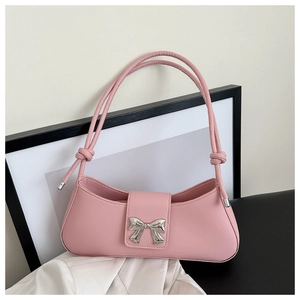 Detail of pink faux leather shoulder bag featuring a silver bow buckle and knotted straps