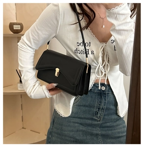 Detail view of the elegant golden metal square clasp on the black shoulder bag