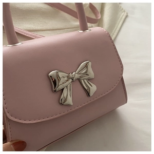 Dettaglio di una mini borsa rosa con grande fiocco in metallo argento e pelle PU liscia