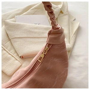 Close-up of pink marble texture faux leather with braided handle and gold zipper detail