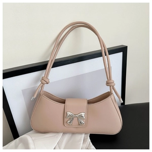 Detail of a beige baguette bag featuring a silver metal bow and knotted shoulder strap