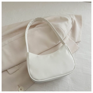 Detailed view of a creamy white crescent hobo bag resting on a textured blazer