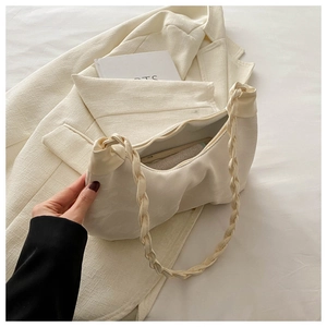 Detailed view of cream pleated underarm bag with woven handle on white aesthetic backdrop