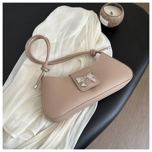 Close-up of elegant pink shoulder bag featuring a silver metal bow buckle and knotted strap