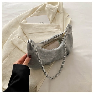 Detail of silver pleated bag featuring braided shoulder strap and gold metal zipper