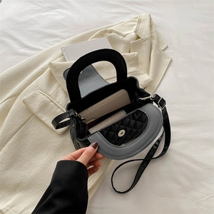 Sac à main matelassé noir avec poignée et bandoulière sur un blazer minimaliste