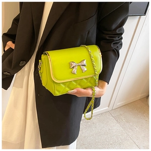 Detail of neon green quilted crossbody bag with silver bow accent and chain strap