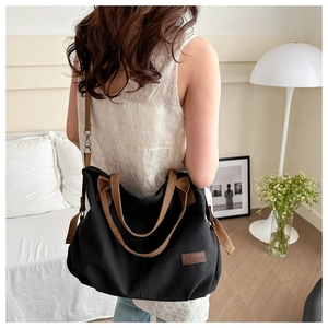 Große schwarze Segeltuchtasche mit braunen Riemen, getragen von einem Model im Haus