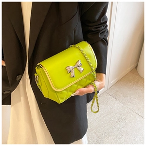 Detail of green mini crossbody bag with silver bow accent and quilted pattern