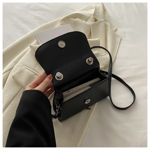 Dettaglio dell'interno di una mini borsa a tracolla nera con chiusure magnetiche