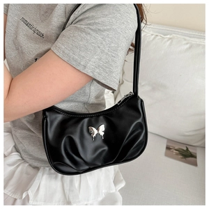 Close-up of black pleated hobo bag with silver butterfly charm on a soft background