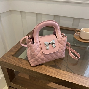 Sac matelassé rose avec nœud en métal sur une table basse en bois au style raffiné