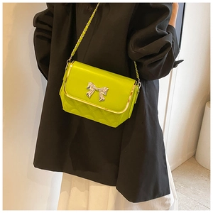 Detail of lime green quilted crossbody bag with silver bow accent and chain strap