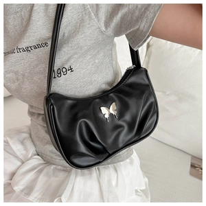 Detail of black pleated shoulder bag featuring a silver metal butterfly buckle accent
